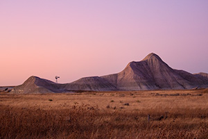 Scenic landscape photograph of a windmill and badlands during dusk in western Nebraska. - Nebraska Photograph