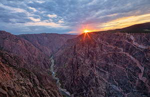 The last bit of sun hangs just above the canyon wall at Black Canyon of the Gunnison National Park on a cool summer evening. - Colorado Landscape Photograph