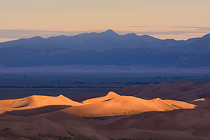 Light graces the tops of the Sand Dunes in the distance as the sun peaks over the Sangre De Cristo range. - Colorado Landscape Photograph