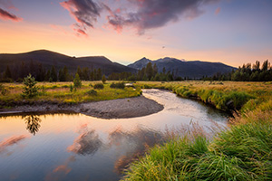 The sun sets behind the Never Summer Range as the Kawunechee River flows through the west side of Rocky Mountain National Park in Colorado. - Colorado Photograph