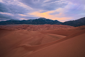 As the last of the light of the day diminishes at Great Sand Dunes National Park, a single set of clouds remain illuminated before quietly going dim. - Colorado Photograph