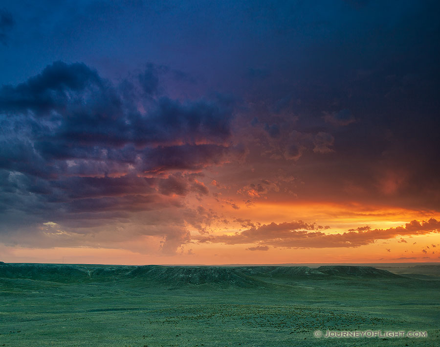 The verdant prairie grass appears as a green carpet in the valleys of Agate Fossil Beds National Monument in western Nebraska as the last bit of sunlight radiates from beneath the dark storm clouds.  From a high perch, I watched this storm as it moved past, the clouds changing and morphing. - Nebraska Photography