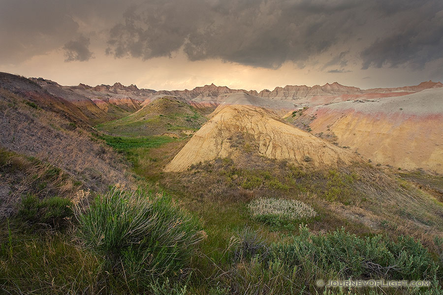 As a storm passes over Badlands National Park in South Dakota, the last light of the day illuminates a few distant clouds. - South Dakota Photography