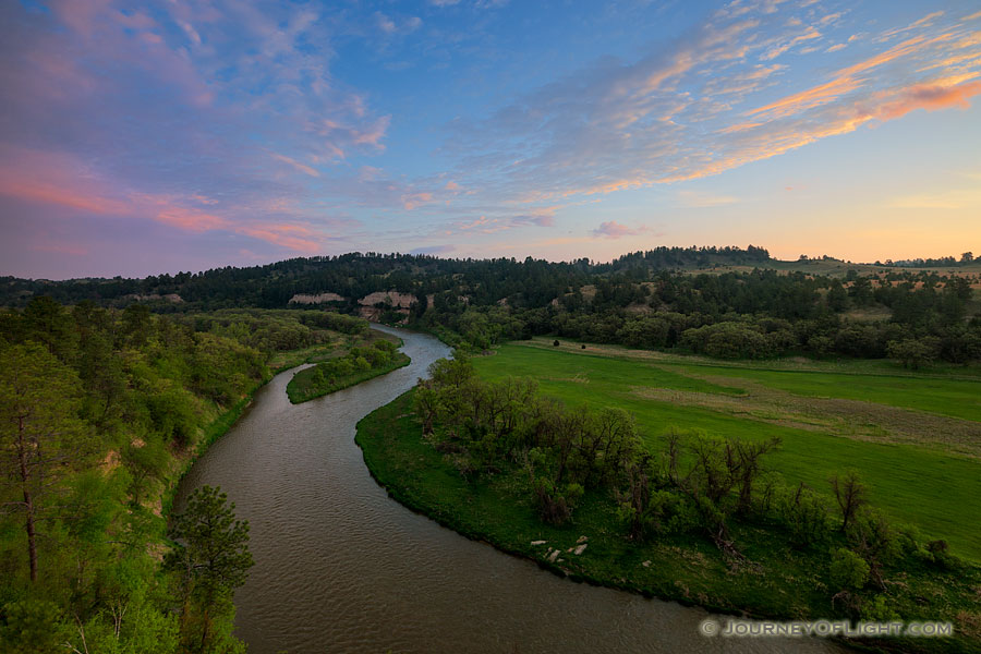 The Niobrara river west of Niobrara National Wildlife Refuge, snakes through a lush green valley on a beautiful spring morning. A cool breeze blew gently as the sun rose in the east illuminating the clouds in the sky. - Valentine Photography