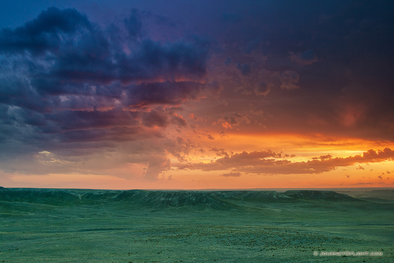 The verdant prairie grass appears as a green carpet in the valleys of Agate Fossil Beds National Monument in western Nebraska as the last bit of sunlight radiates from beneath the dark storm clouds.  From a high perch, I watched this storm as it moved past, the clouds changing and morphing. - Nebraska Picture