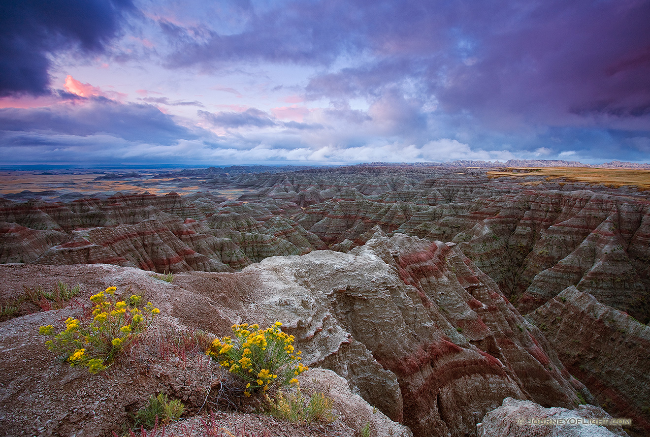 On a cool morning, the smell of a past rain fills the air.  The sunrise illuminates the passing storm clouds at Badlands National Park, South Dakota. - Badlands NP Picture