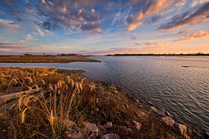 Bright puffy clouds float across the sky as the morning sun rises over the Missouri at Ponca State Park in northeastern Nebraska. - Nebraska Photograph