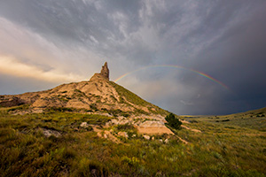 A scenic landscape Nebraska photograph of a rainbow over Chimney Rock in western Nebraska. - Nebraska Photograph