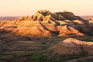 Light from the recently risen sun illuminates the Badlands in South Dakota with a warm orange hue. - South Dakota Photograph
