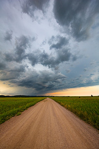 A landscape photograph of an intense summer storm rages over a rural country road in South Dakota. - South Dakota Photograph