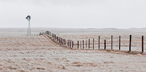Scenic landscape panoramic photograph of a windmill and a fence in the winter at Oglala National Grasslands. - Nebraska Photograph