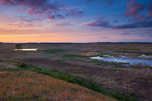 As twilight approaches, clouds float lazily above Valentine National Wildlife Refuge and reflect the pinks and purples of sunset. - Nebraska Photograph