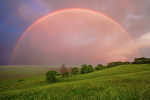 After an intense midwestern spring storm, from a Nebraska hilltop, an entire rainbow arches through the sky. - Nebraska Photograph