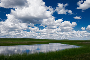 Clouds float lazily above a lake in the Sandhills of Nebraska. - Nebraska Photograph