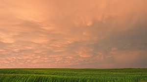 Passing ominous storm clouds reflect the red and orange hues of the sun 45 minutes after sunset. - Nebraska Photograph
