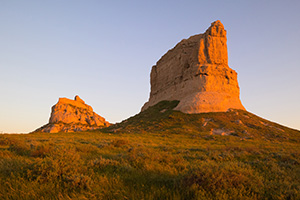Jailhouse and Courthouse Rock both glow red with the first light at sunrise. - Nebraska Photograph