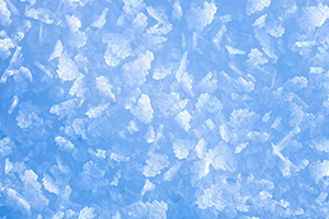 Different shapes and sizes of snowflakes stick to the top of a snow bank, each one glistening in the early morning sun. - Nebraska Photograph