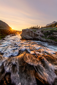 A scenic landscape photograph of sunrise over a waterfall Swiftcurrent Lake, Glacier National Park, Montana. - Northwest Photograph